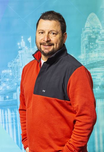 A man wearing a red and navy sweater with a black collar.